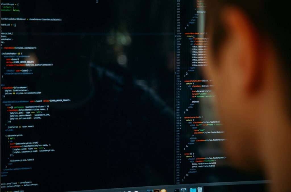 Vue par-dessus l'épaule d'une personne analysant des lignes de code informatique sur un écran, illustrant un guide débutant IA pour la programmation.