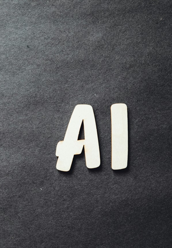 Lettres en bois formant le sigle "AI" posées sur un fond texturé noir, illustrant une sélection des meilleurs logiciels IA actuels.