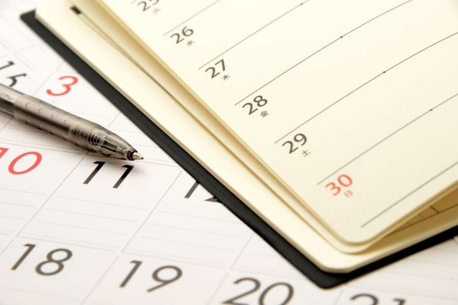 Un stylo posé en gros plan sur un calendrier entreprise personnalisé ouvert pour planifier les rendez-vous professionnels.