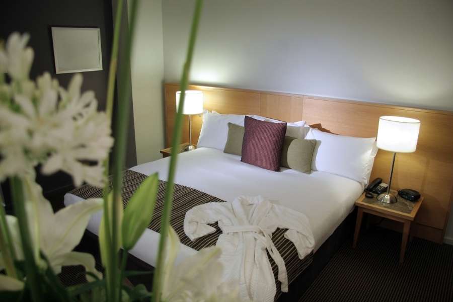 Une chambre d'hôtel élégante avec un lit douillet mettant en avant des hébergements écoresponsables.